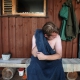 A man wrapped in a towel sits outside on the sauna terrace after a steam session, drying his neck with a towel.
