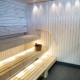 The bright and modern sauna features light wooden walls and benches, with a wooden water bucket placed on the bench for throwing steam.
