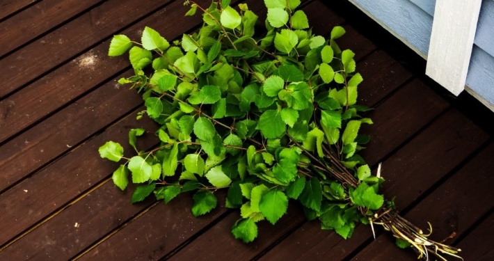 A birch whisk made from fresh branches placed on the wooden sauna terrace.