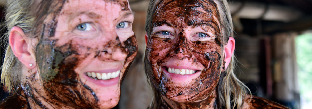 A close-up of smiling people with peat applied to their faces