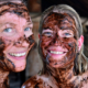 A close-up of smiling people with peat applied to their faces