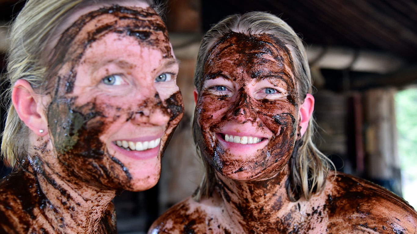 A close-up of smiling people with peat applied to their faces